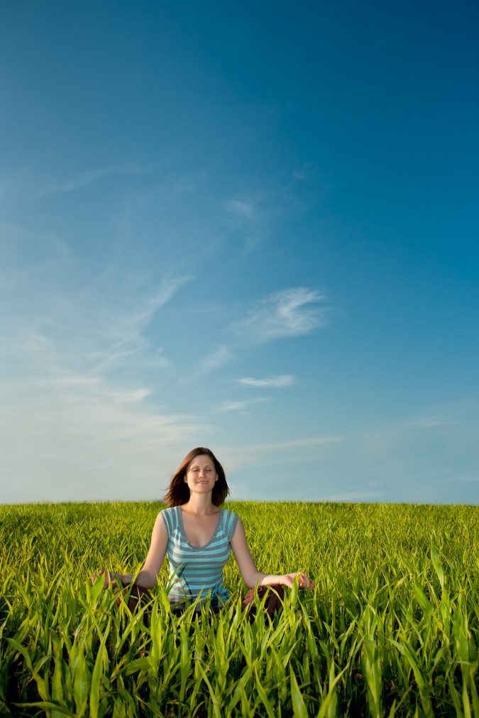 woman on green field under blue skies